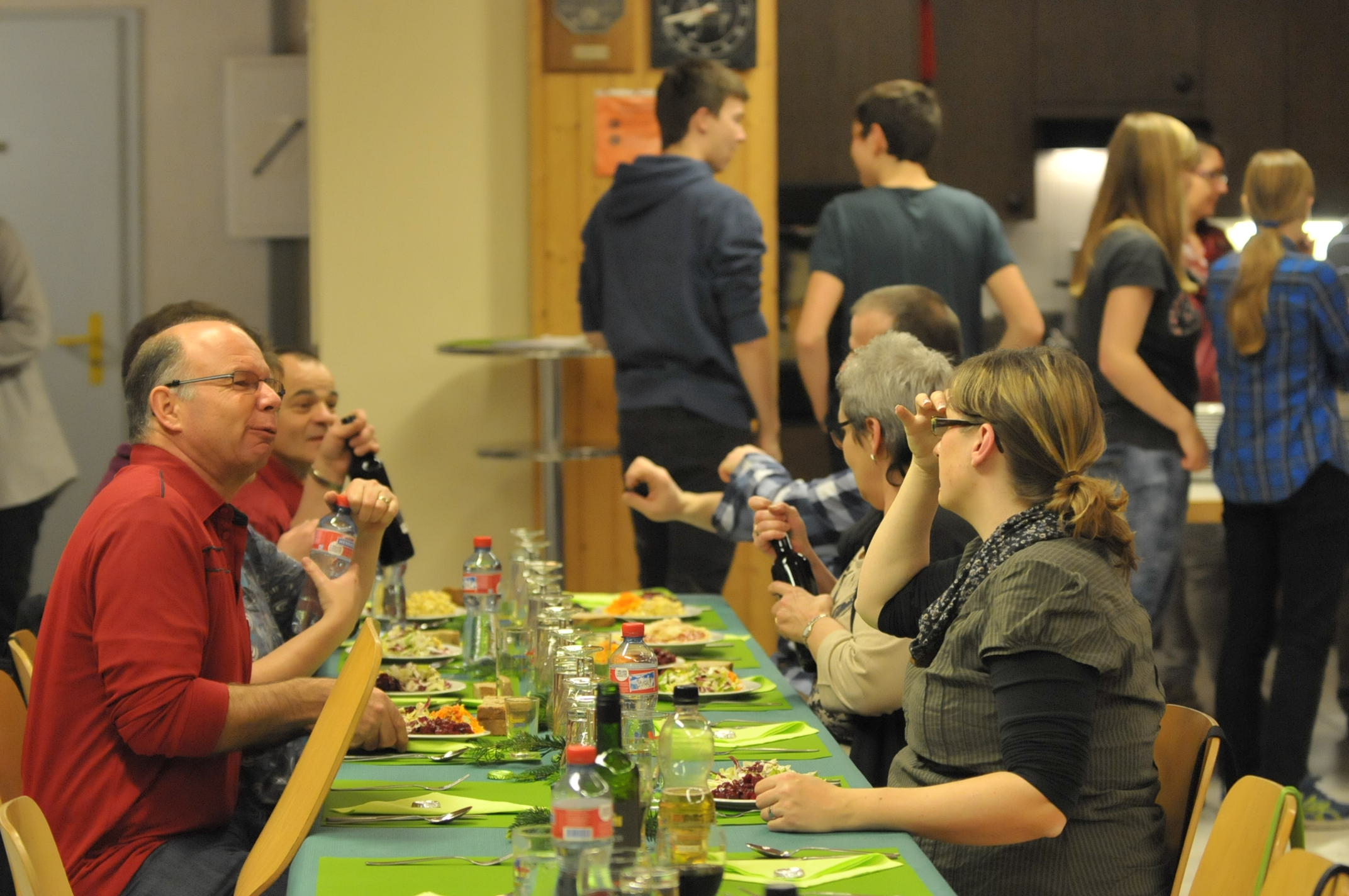 Mitglieder sitzen an langem Tisch mit grünem Tischtuch