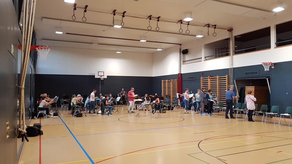 Totalaufnahme der Turnhalle. Ganz hinten sitzen bereits ein paar Musizierende.